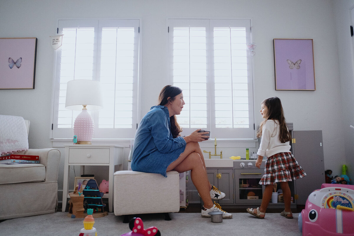 A mom and daughter play together in her bedroom.