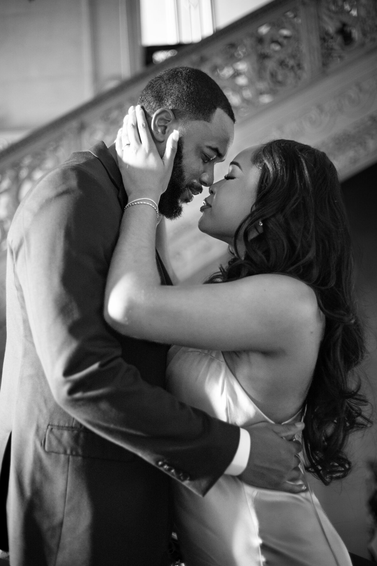 Ochre Court Mansion  | Kelsey Sheehan Photography Timeless Rhode Island Weddings | A couple embraces intimately in a black-and-white photo. The woman gently holds the man's face, both gazing into each other's eyes, conveying deep affection.