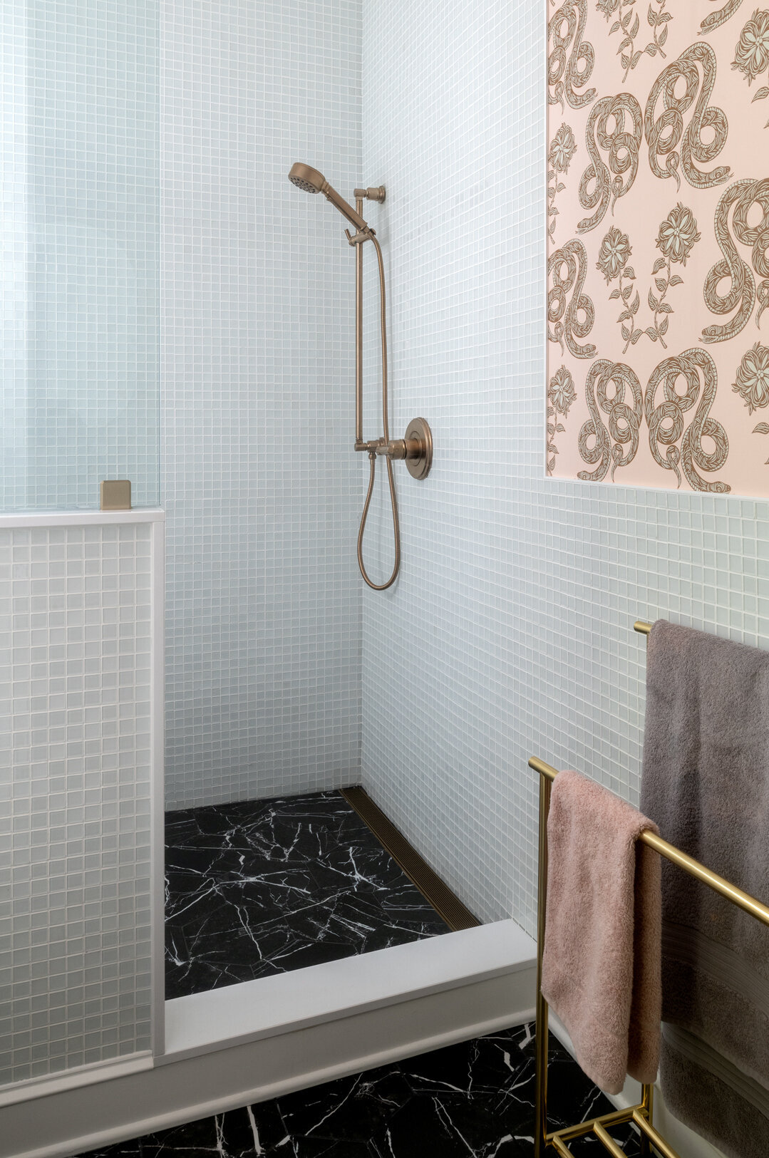 baby blue tiled shower with black marble floor and light pink patterned wall