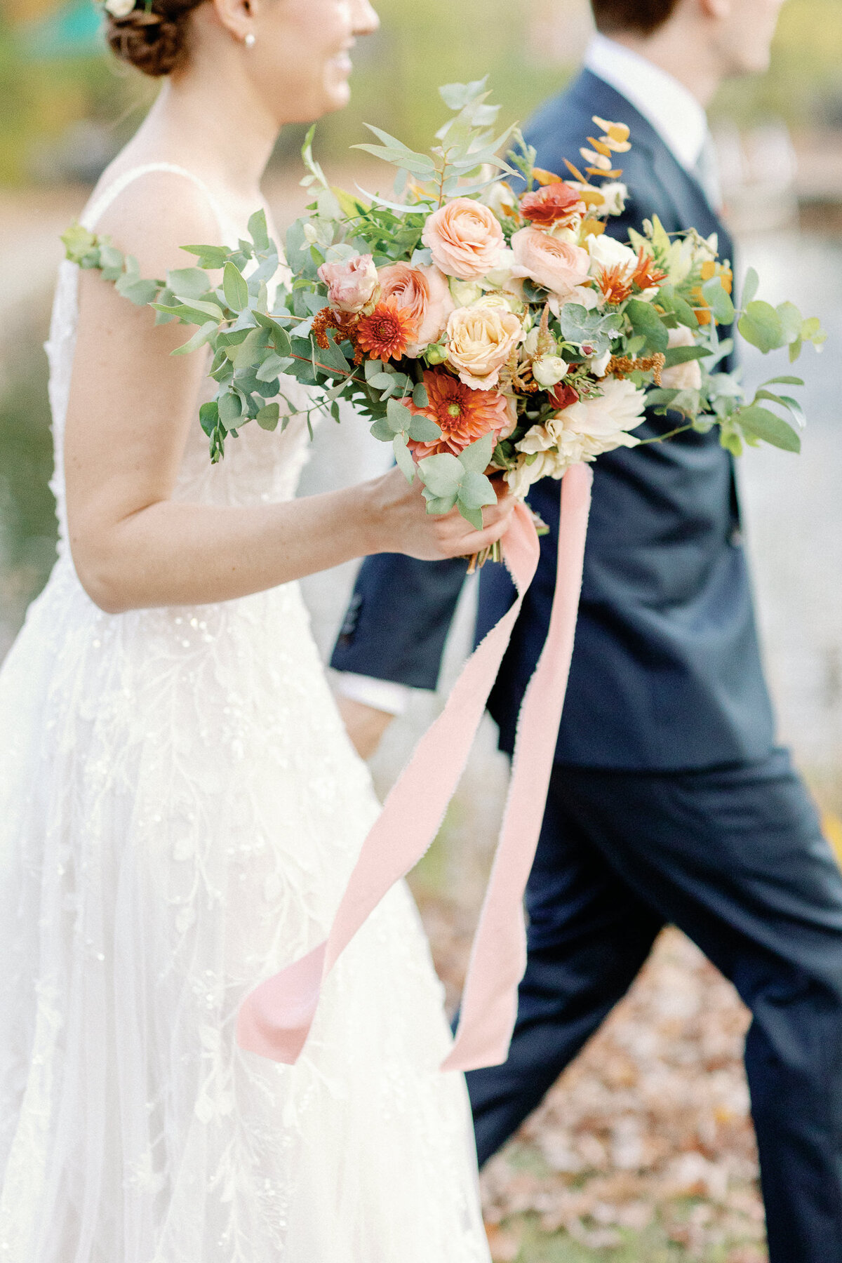 A candid capture of a bride walking with groom. The image is focused on the bride's bouquet