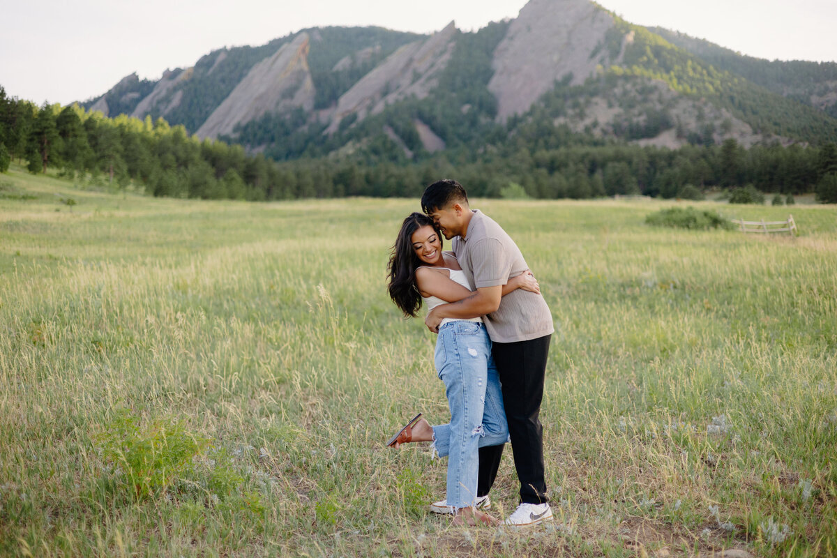 An engaged couple shares a joyful and playful embrace on Chautauqua Trail in Boulder, Colorado, during their engagement session.