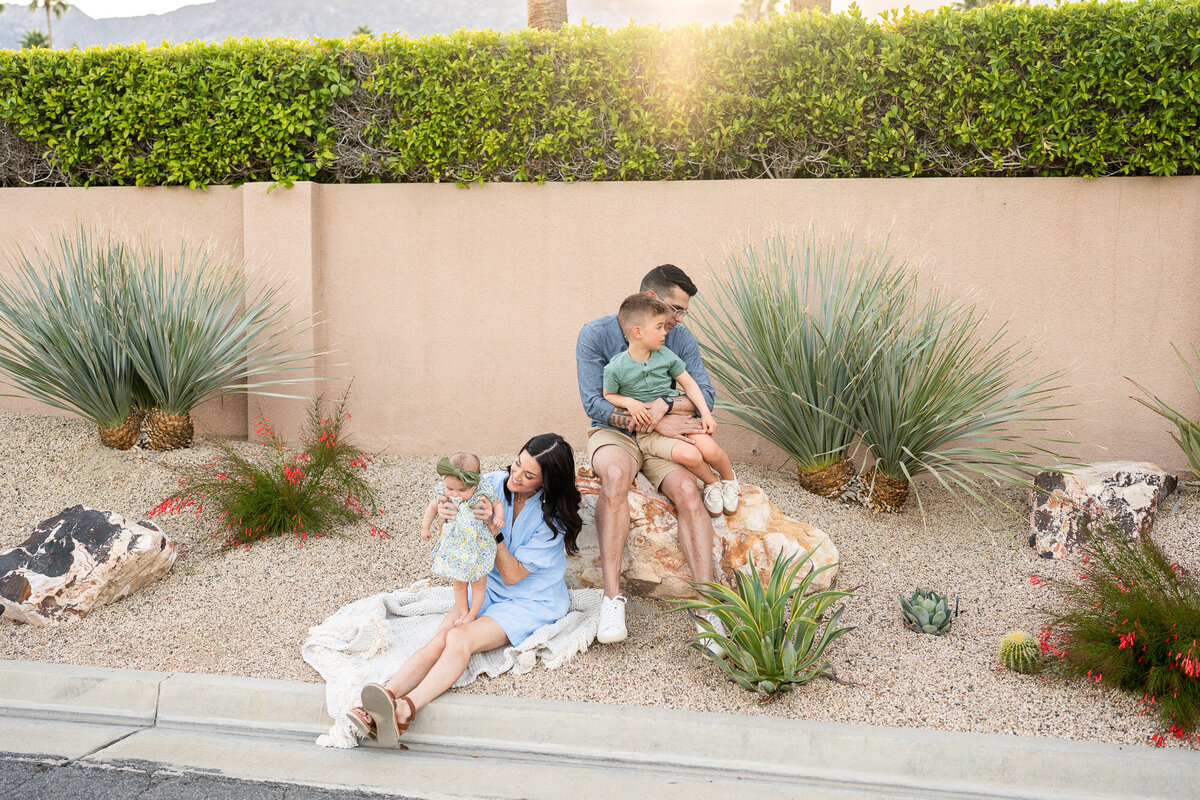 Palm Springs family photographer captures a young family on vacation while sitting next to desert plants. 