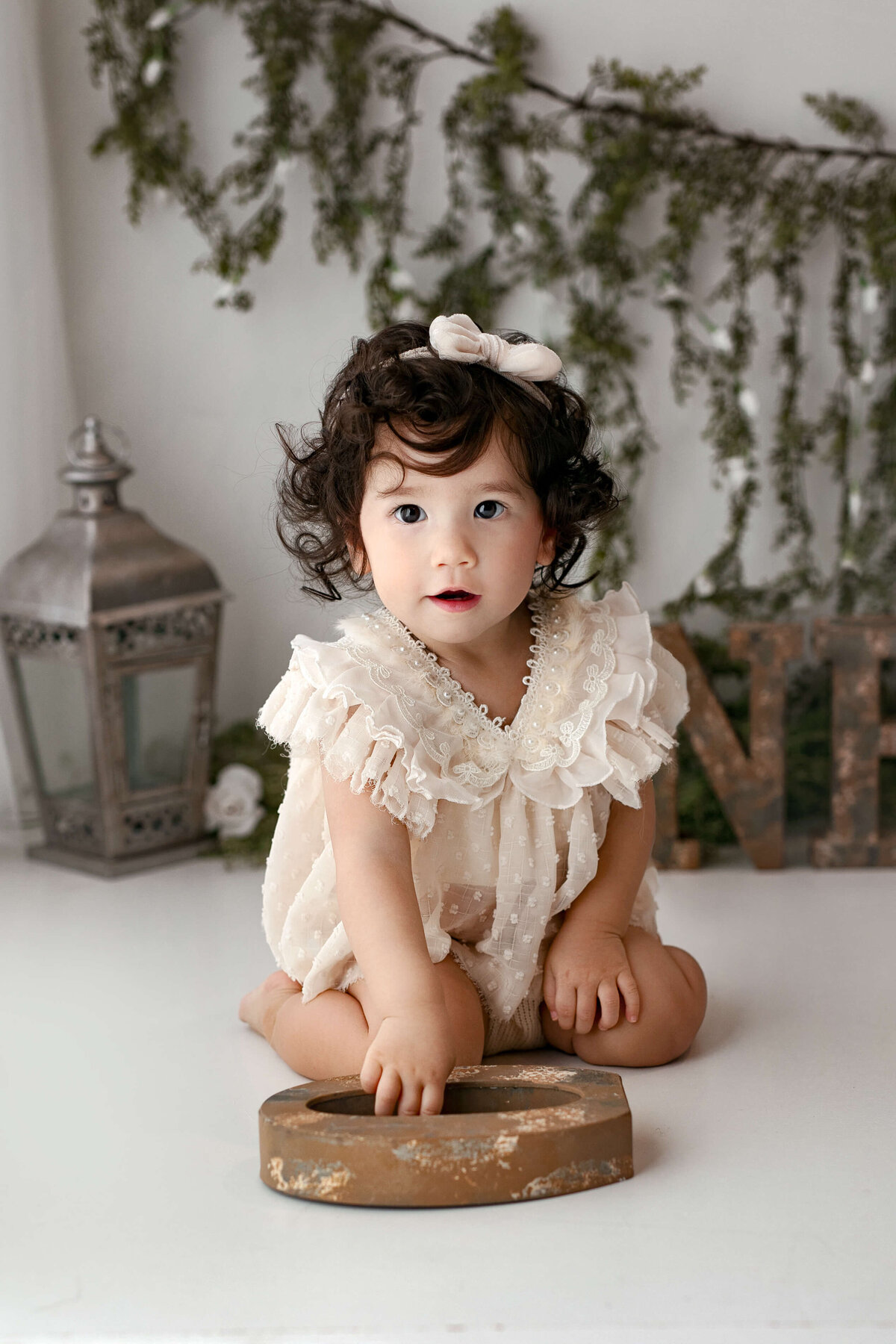 little girl sitting on her knees playing with a one letter during her toddler milestone session