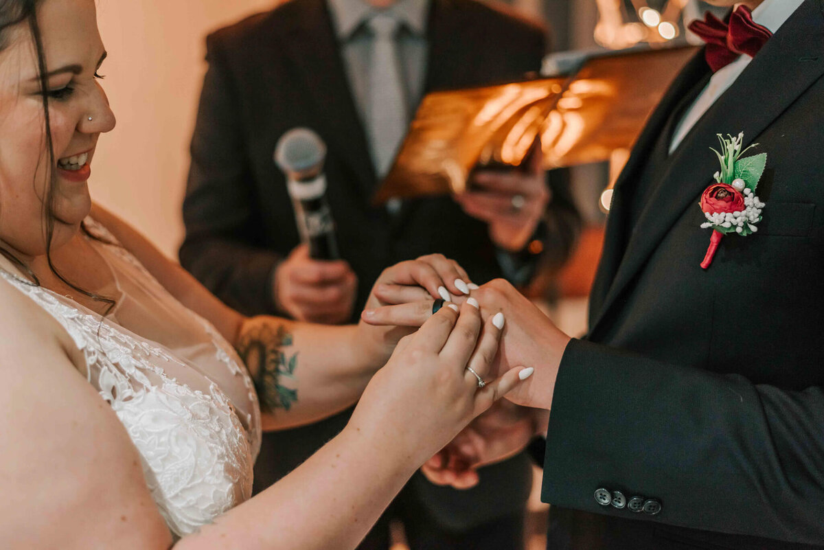Bride placing ring on grooms finger.