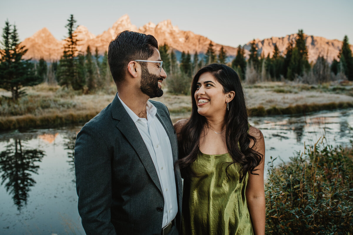man and woman smiling at each other in Jackson Hole for their fall engagement session