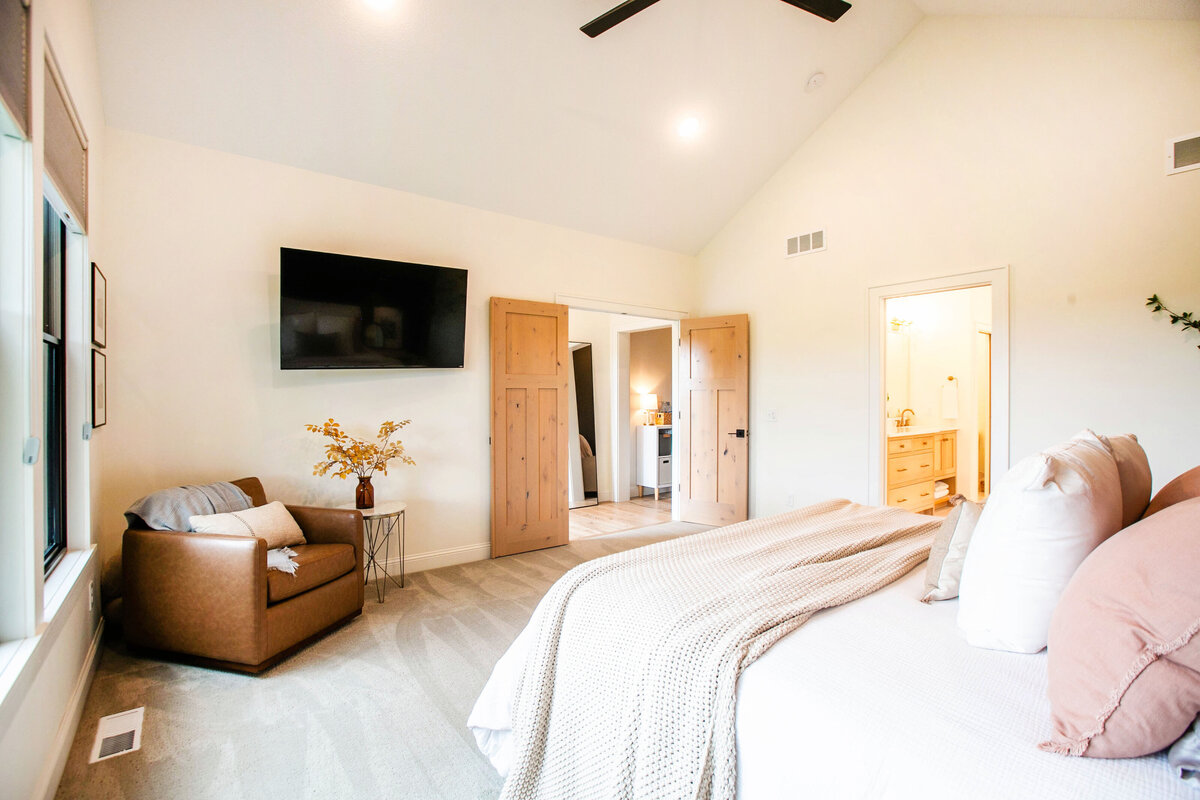 Spacious primary bedroom in custom Otsego home with natural light, wood floors and raised ceiling