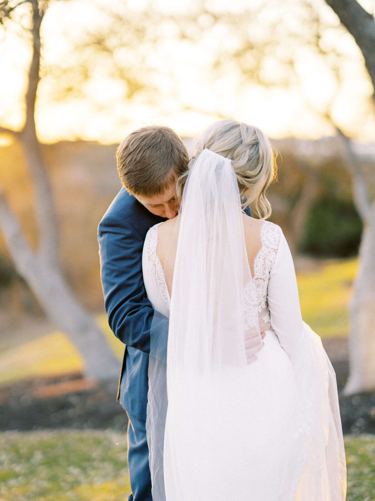 Bride and groom embrace in front of a sunset at Canyonwood Ridge in Texas