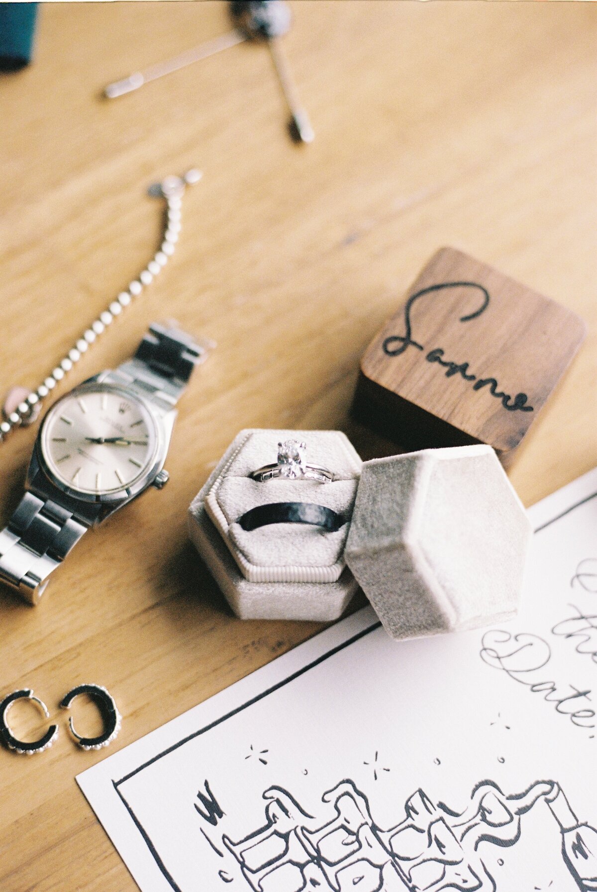 close up of wedding band and ring, watch, earrings, save the date