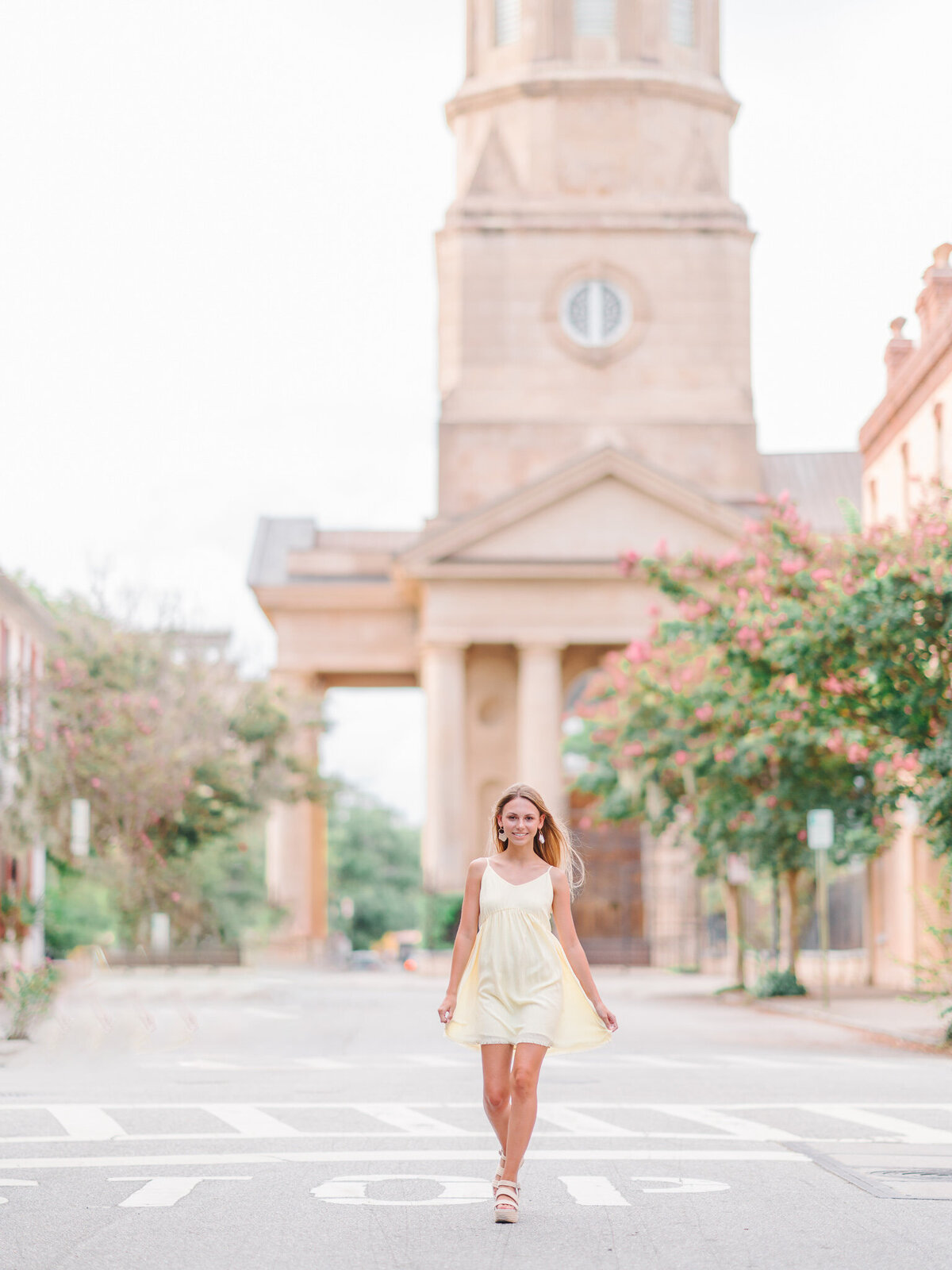 High school senior walking confidently in front of Charleston’s historic clock tower