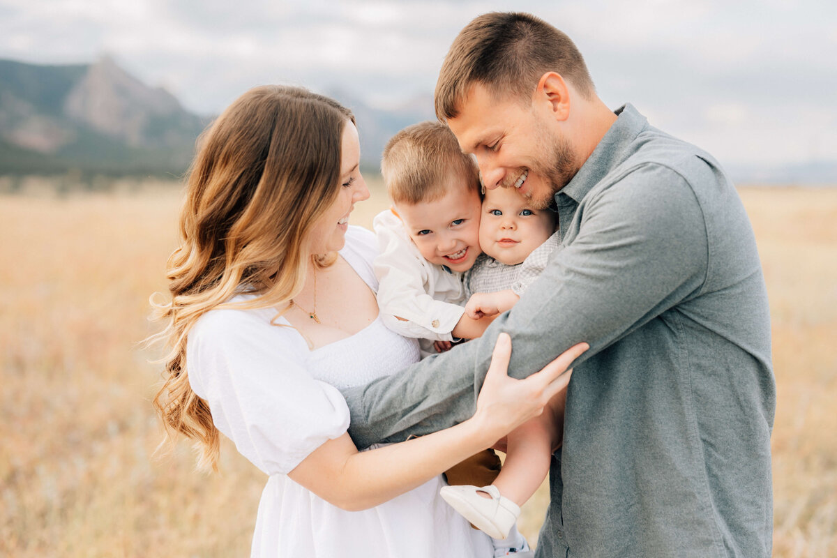 mother holding her two children in a field with dad hugging them sideways