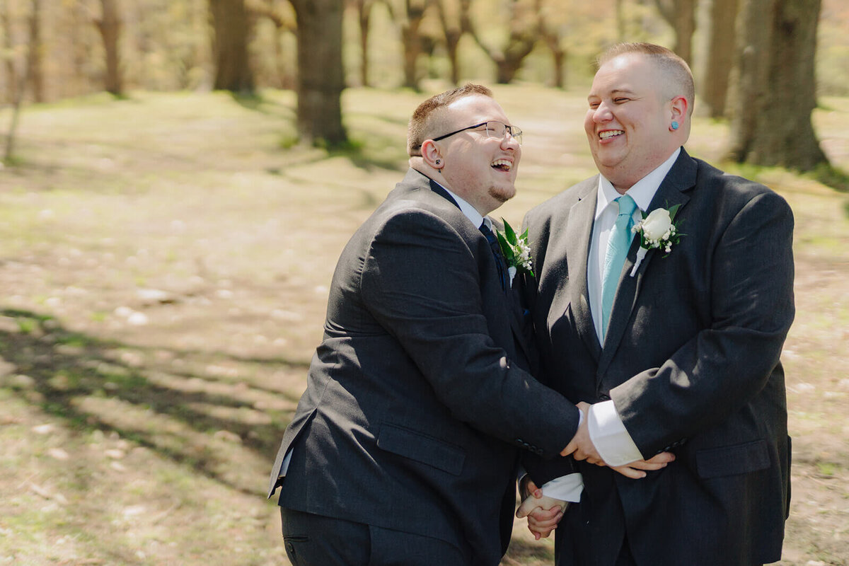 LGBTQ+ couple holding hands walking through forest at Rochester NY wedding