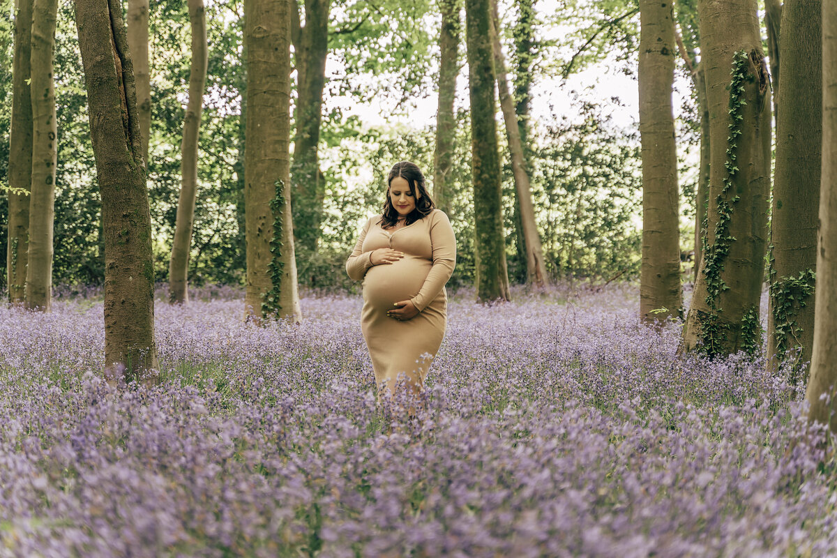 Maternity picture of lady in yellow dress in field of bluebells