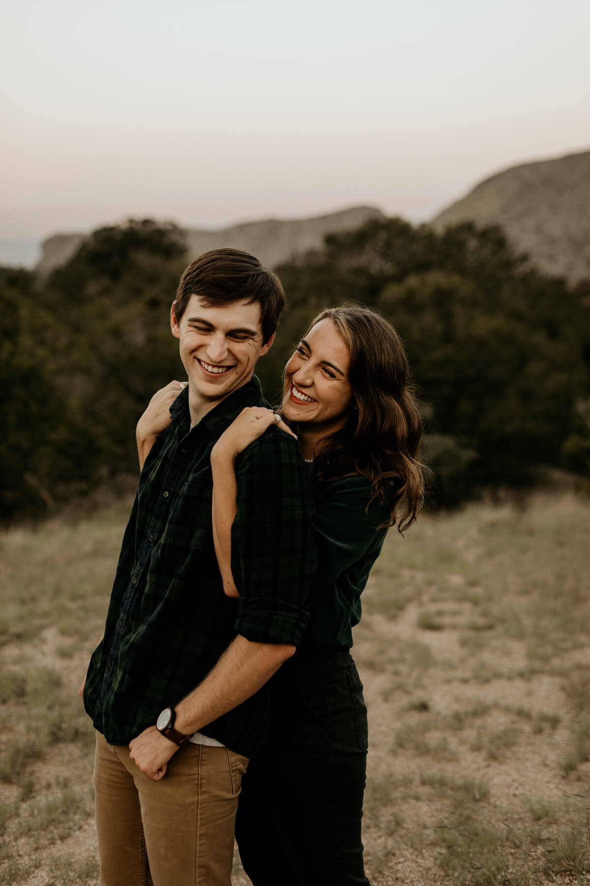 woman hugging her fiancé from behind laughing