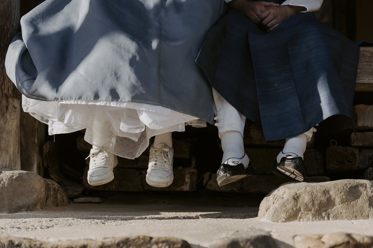 the bride wearing her white sneakers while the groom wearing his black and white shoes