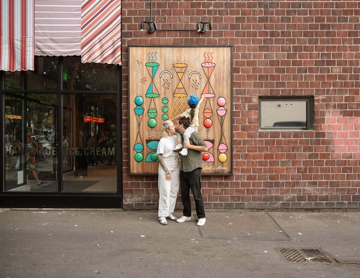 a male and a female with little boy on shoulders outside local ice cream shop