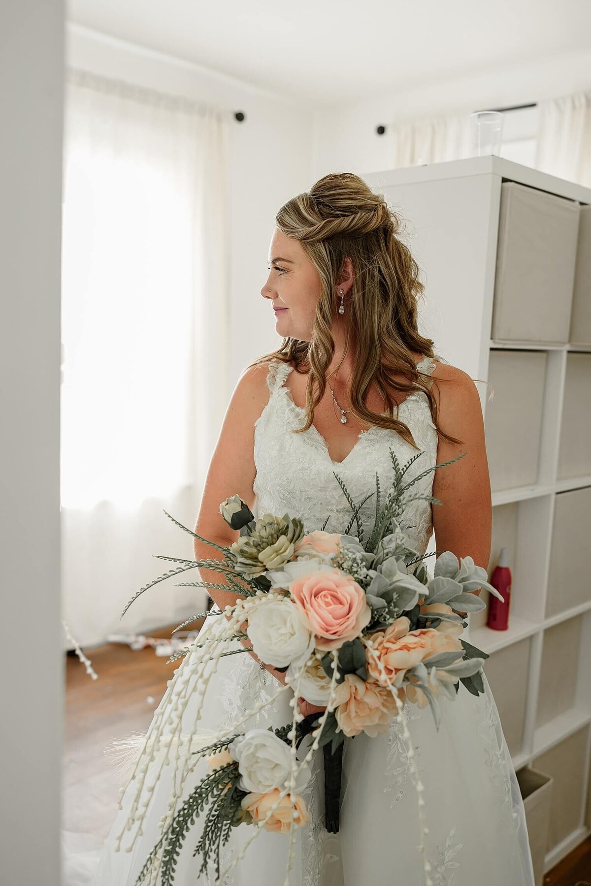 Wedding photo of bride looking out the window holding her bouquet