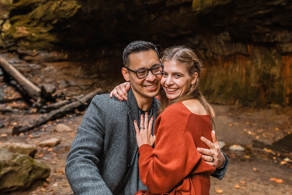 Couple shares a hug while sitting closely in a rocky gorge.