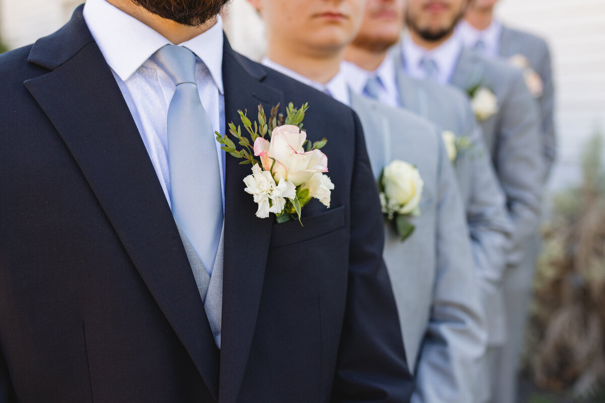 black and gray suit and tuxes lined up to show off boutonnières