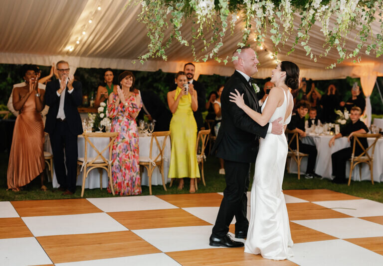 Wedding guests surround the dance floor, cheering and clapping as the newlyweds celebrate their love in a magical first dance moment. Florida Keys destination wedding photography by Claudia Amalia Photography.