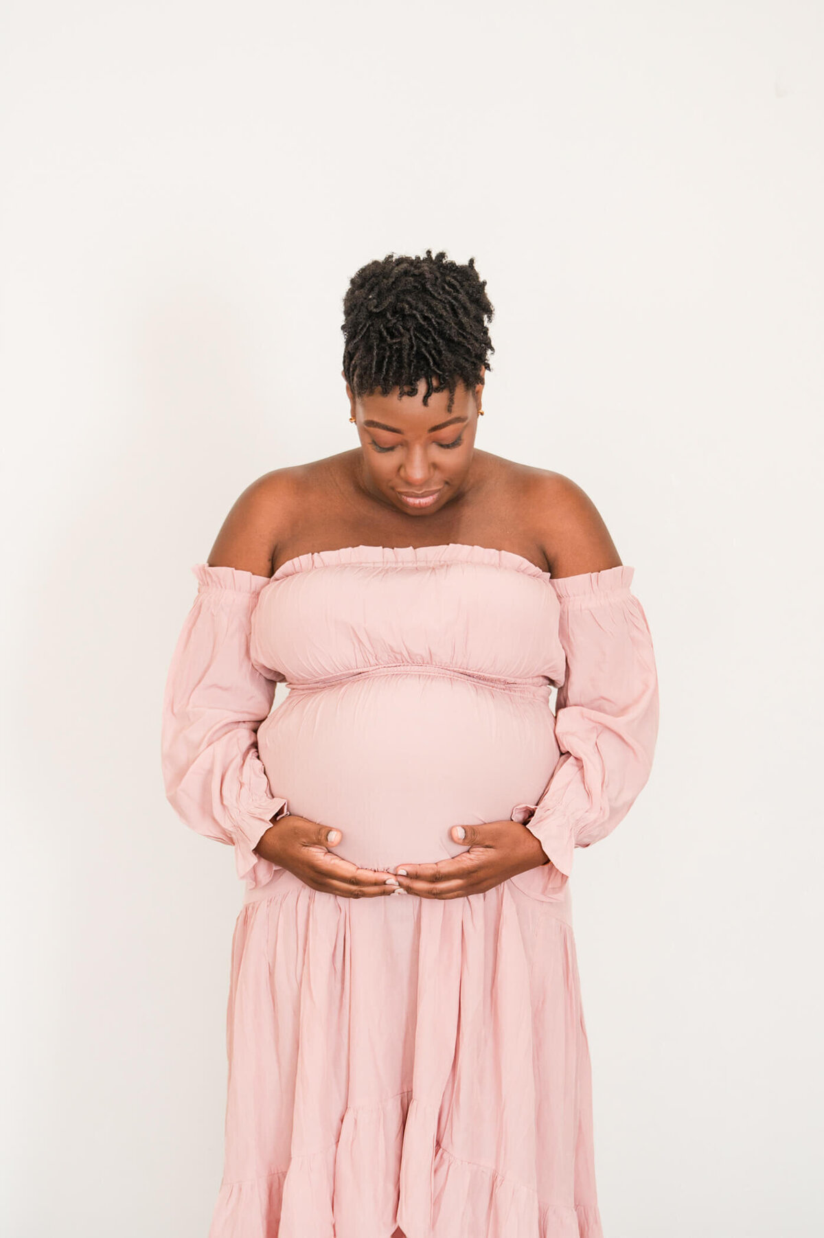 woman looking down at her maternity bump and holding it