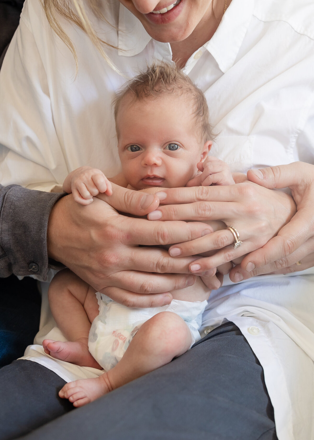 Parents wrap their hands around their baby