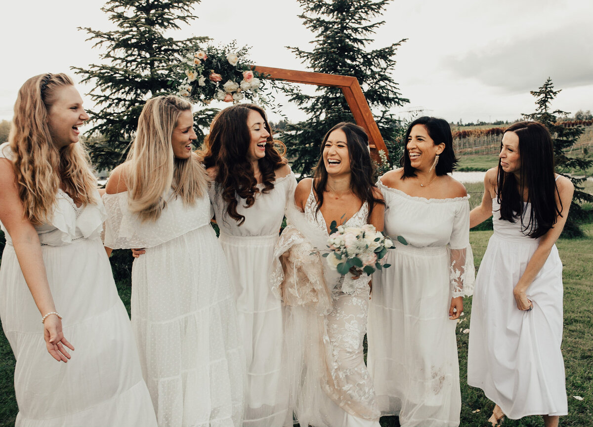 Bridesmaids laughing together all while wearing white
