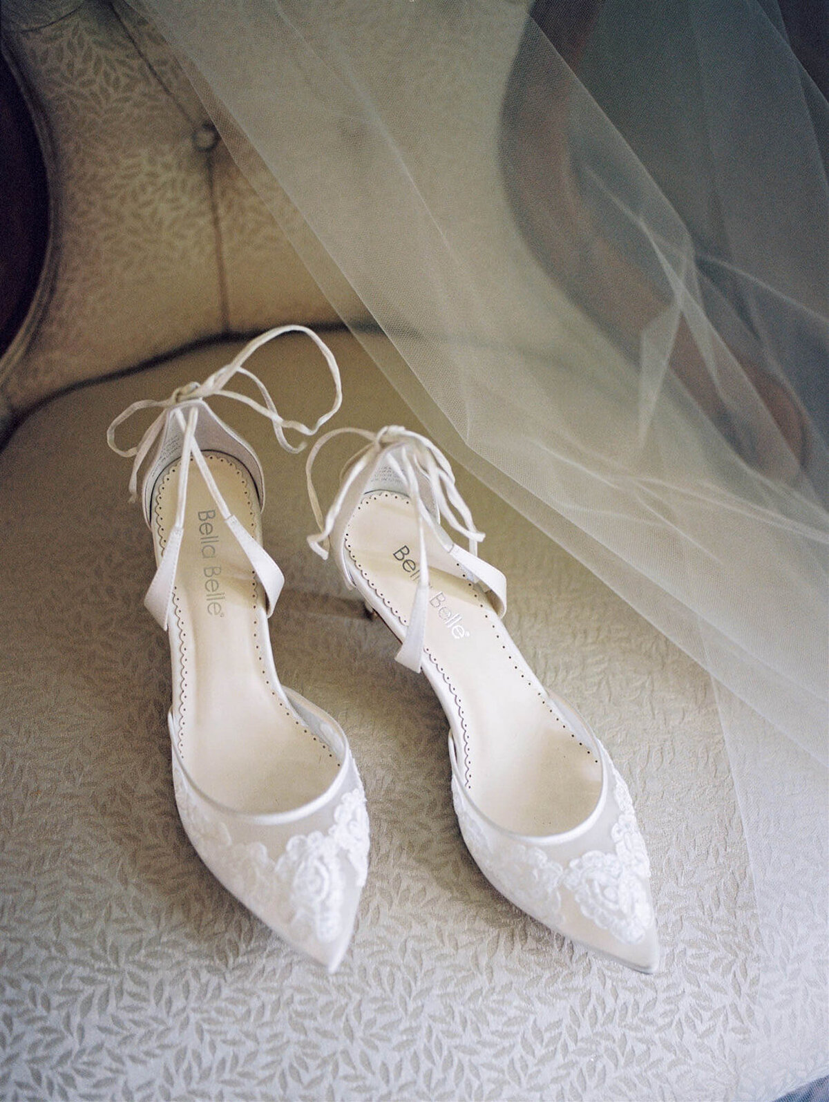 Bridal shoes on chair with veil on the background