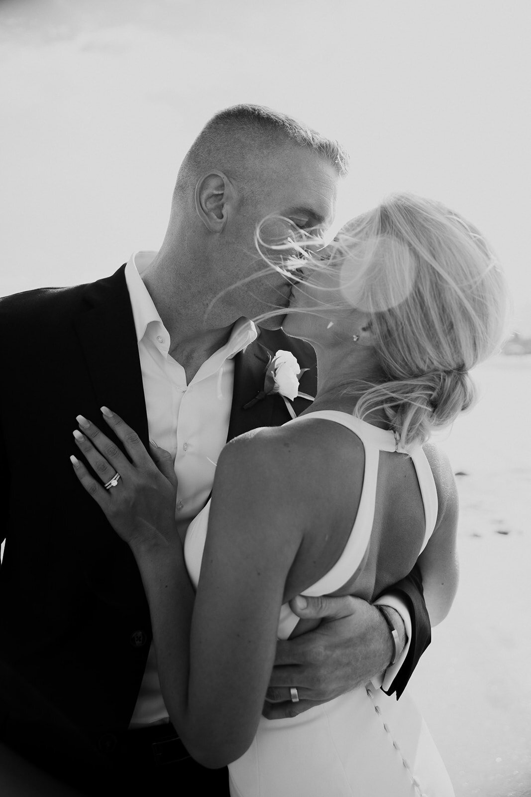 Groom pulls bride in for kiss  at the beach