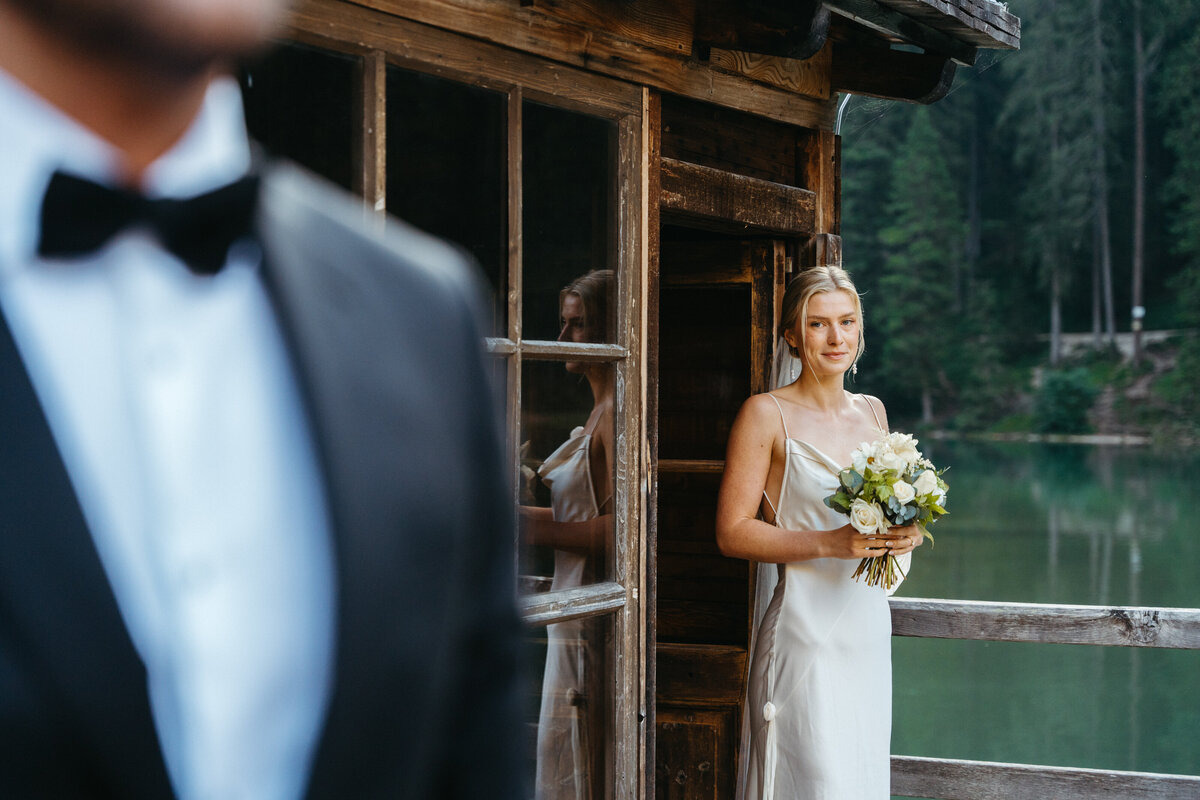 Bride looking out window holding bouquet at Lago di Braies