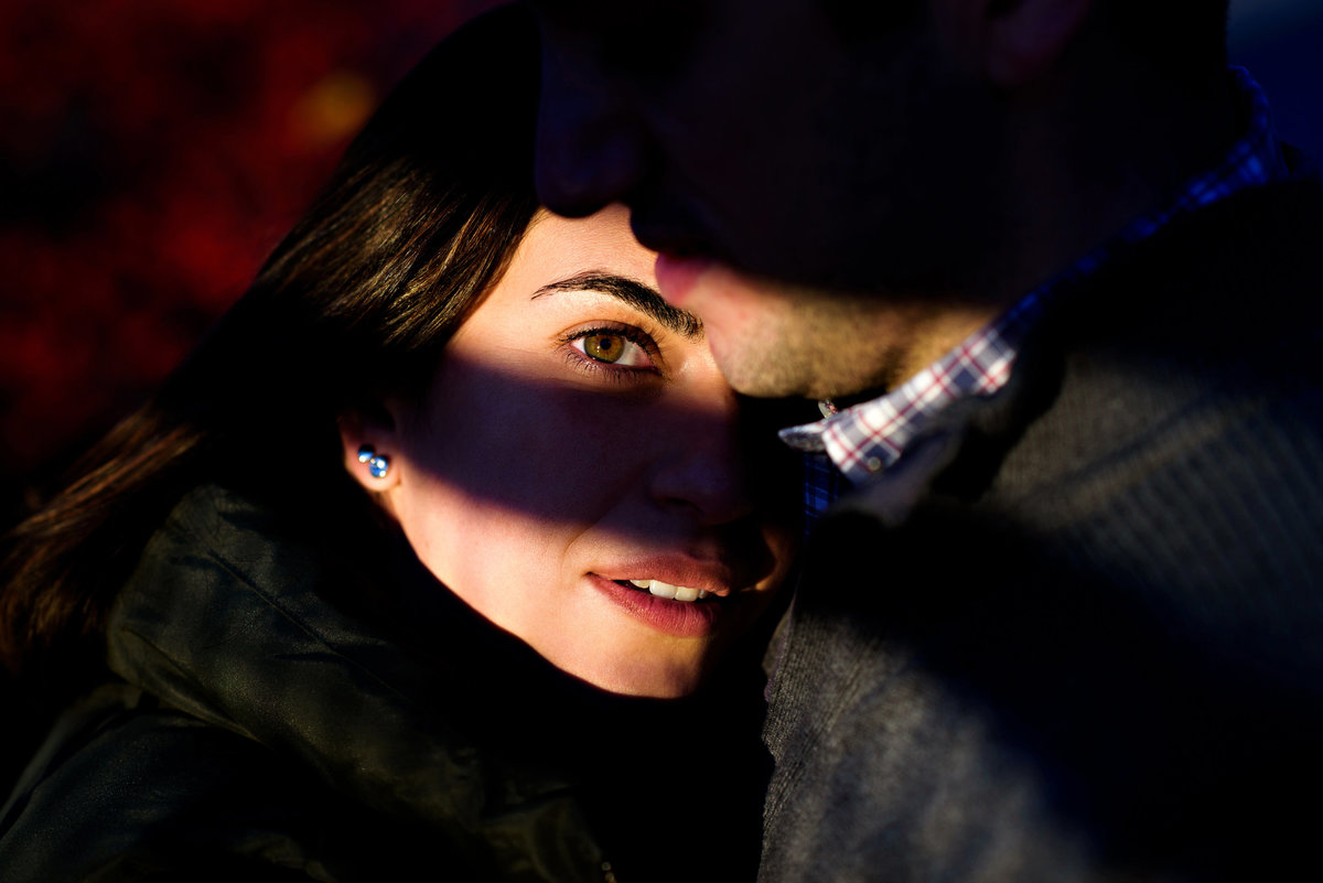 A shadow frames a bride to be's eyes as she lays on her fiance's chest.