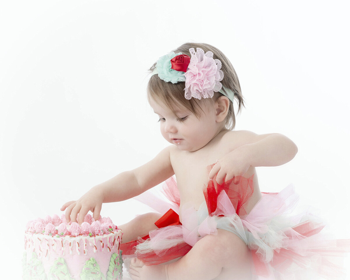 Girl grabs frosting off her cake as she sits on the ground