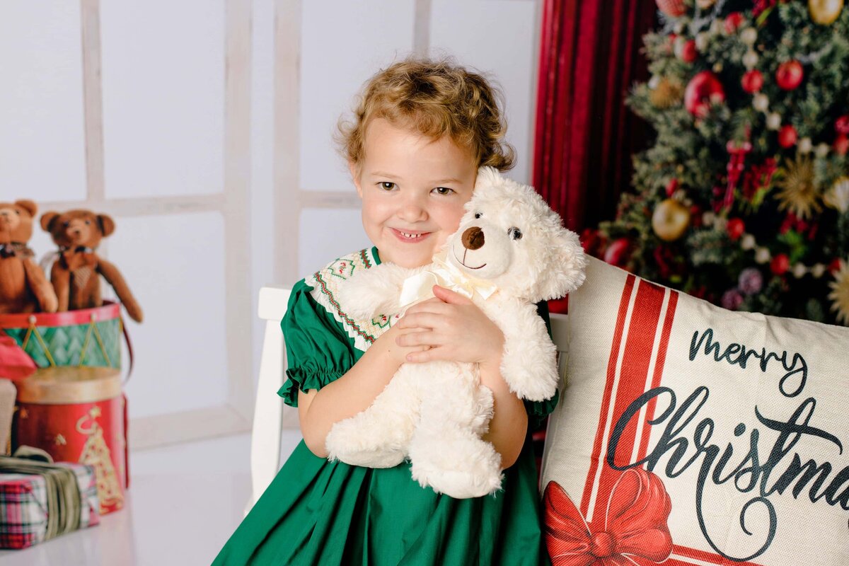 little girl wearing green dress snuggles teddy bear 