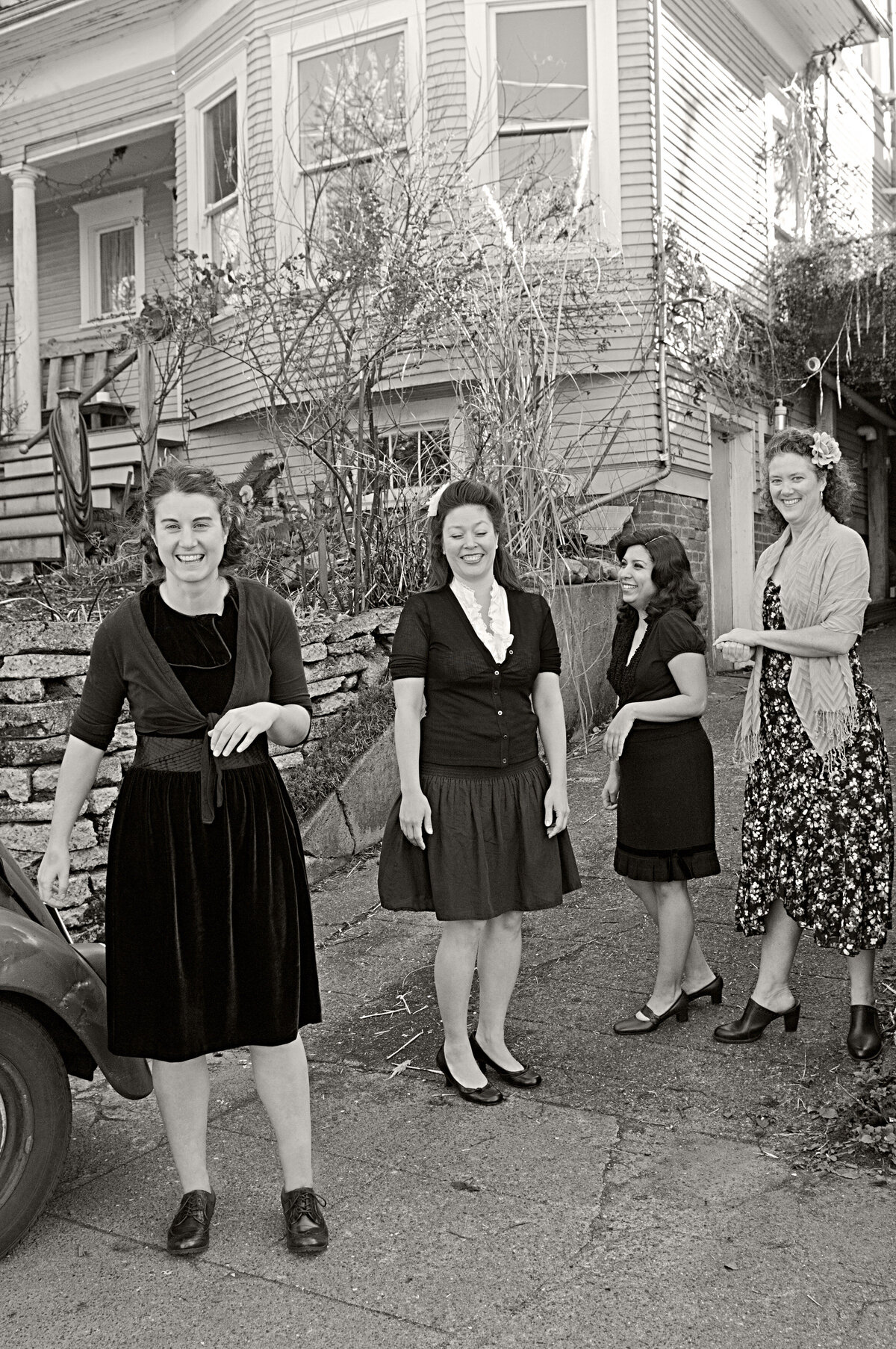 A group of women laughing while standing in a driveway