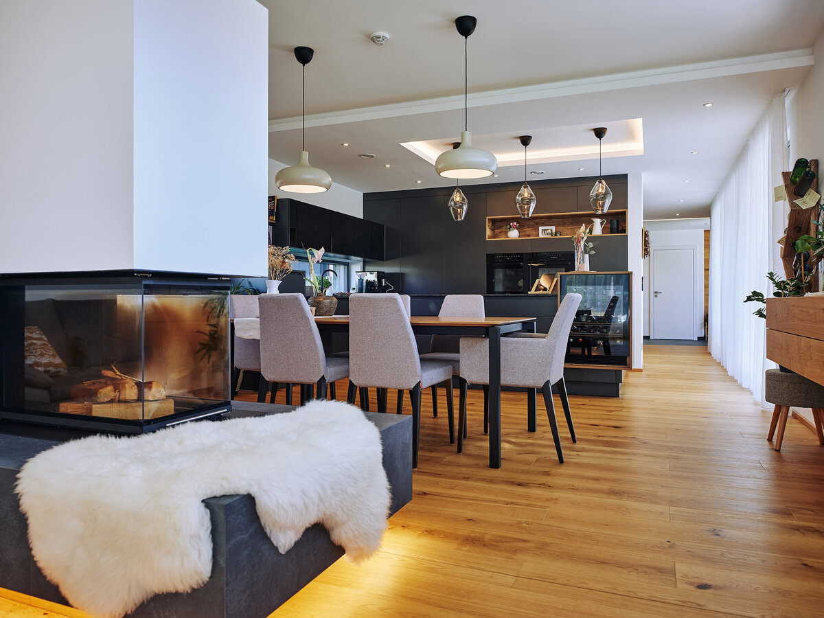 Modernes Wohnzimmer mit dreiseitigem Kamin, Designsofa und hellem Tageslicht – stilvolle Interiorfotografie für Architektur- und Wohnbauprojekte in ganz Österreich