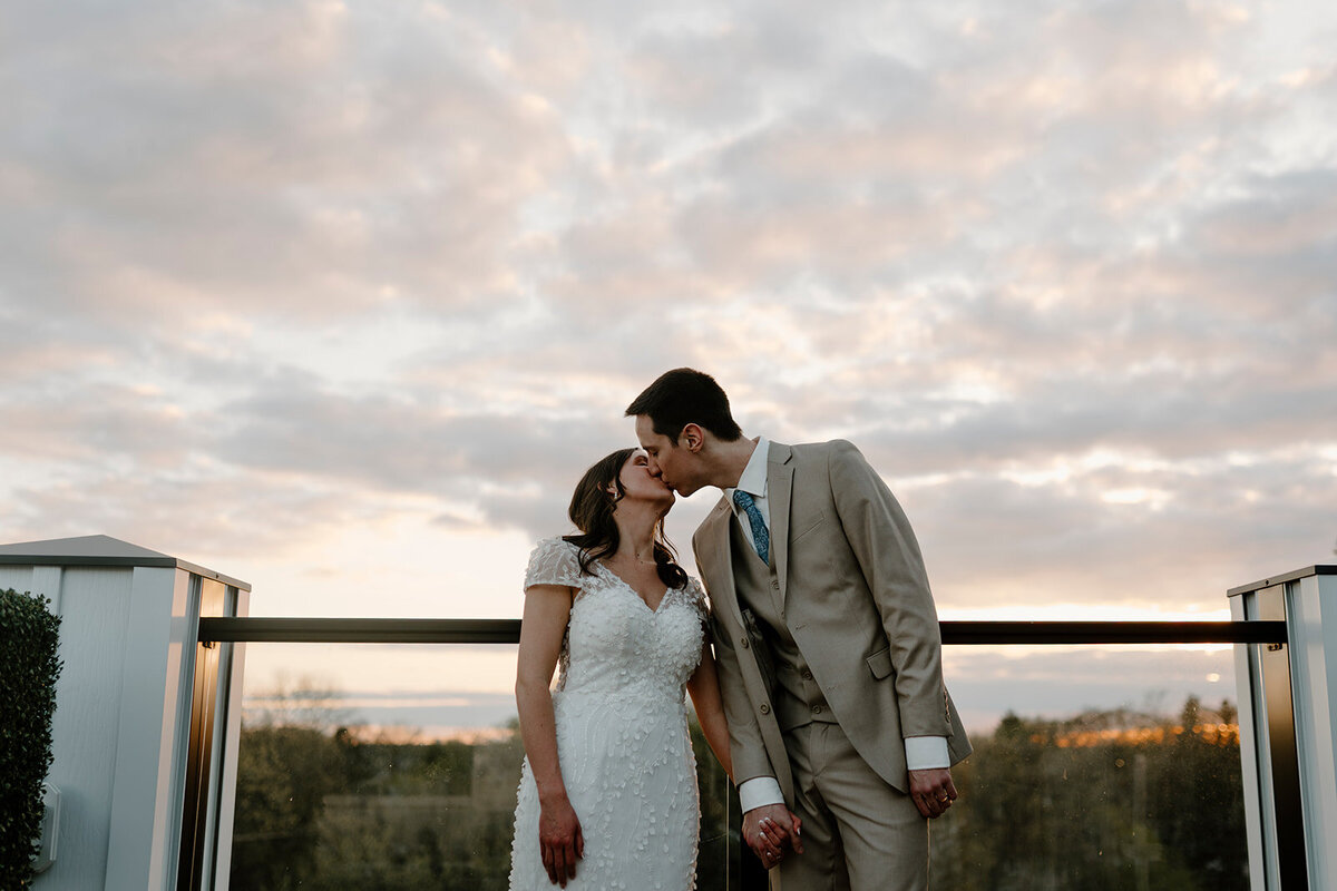 bride and groom kissing at sunset