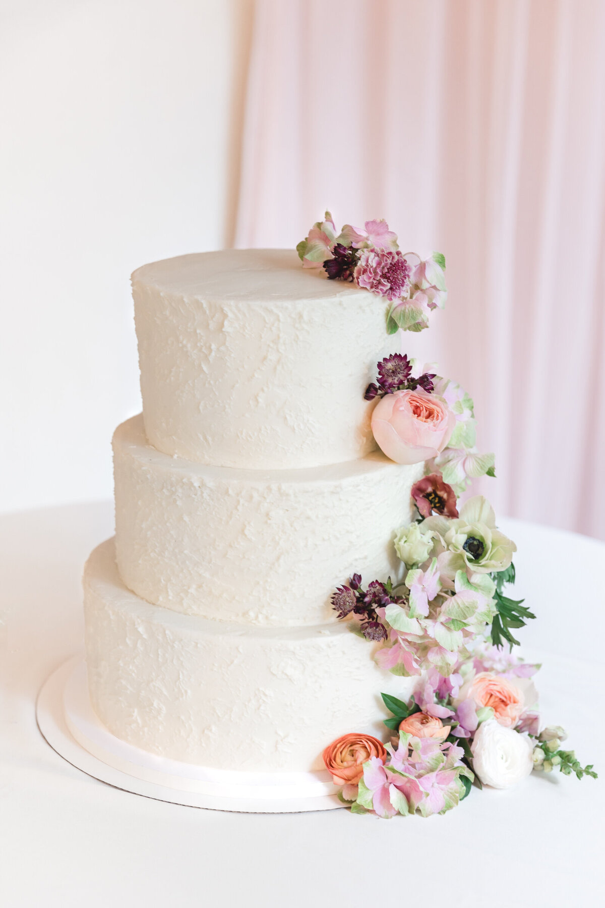 Romantic wedding cake with flowers cascading down the side for a garden wedding in New Hampshire