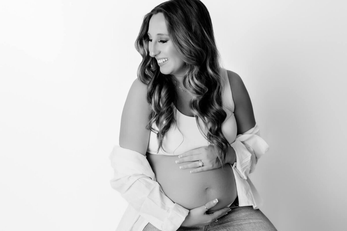 Mom maternity session smiling while cuddling baby bump