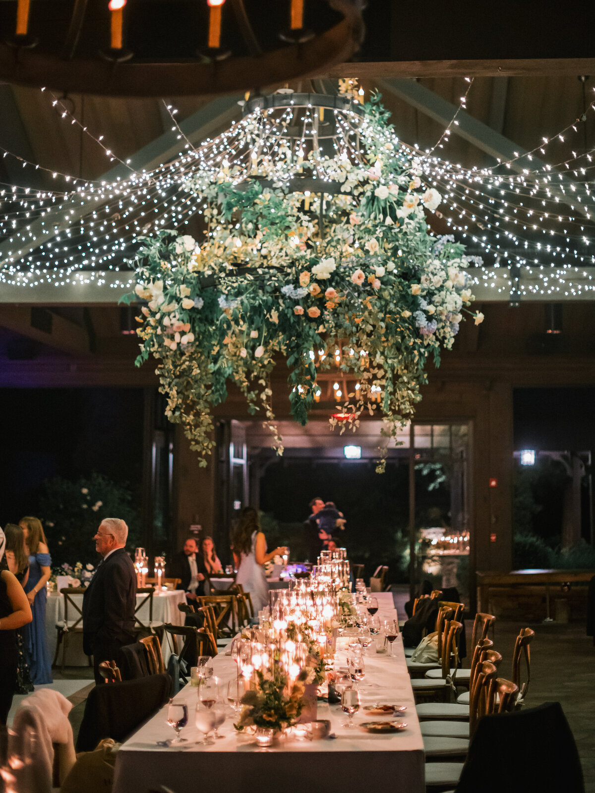 Wedding reception tables lined with candlelight beneath a floral chandelier and twinkle lights at Old Edwards Inn in Highlands, North Carolina.
