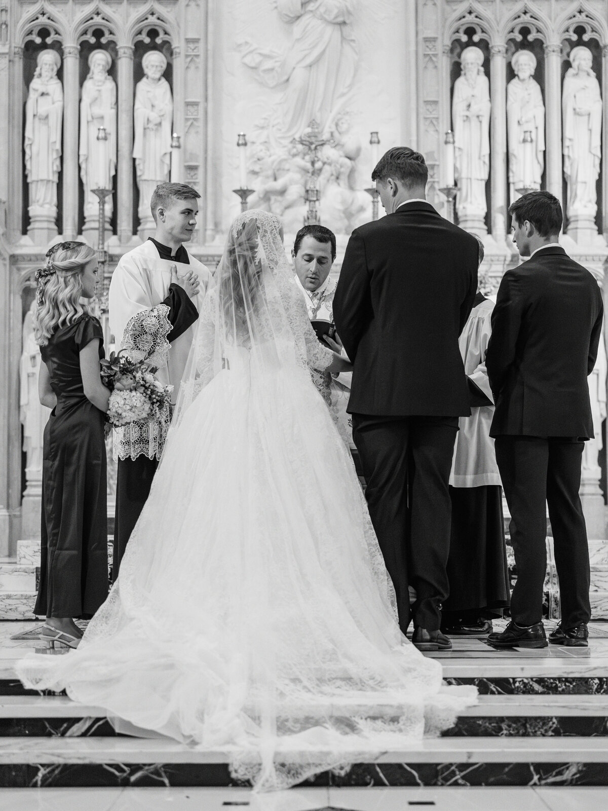 Bride and groom standing at altar with best man and maid of honor during traditional Latin Mass wedding at Our Lady of the Assumption Church in Walton, KY