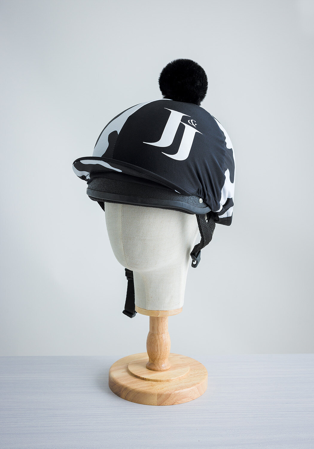 Product shots for Jockey&Jill. Taken in studio by photographer Claire Howes, Norwich. The image is a of a riding hat & cover on a wooden block stand on a white background.
