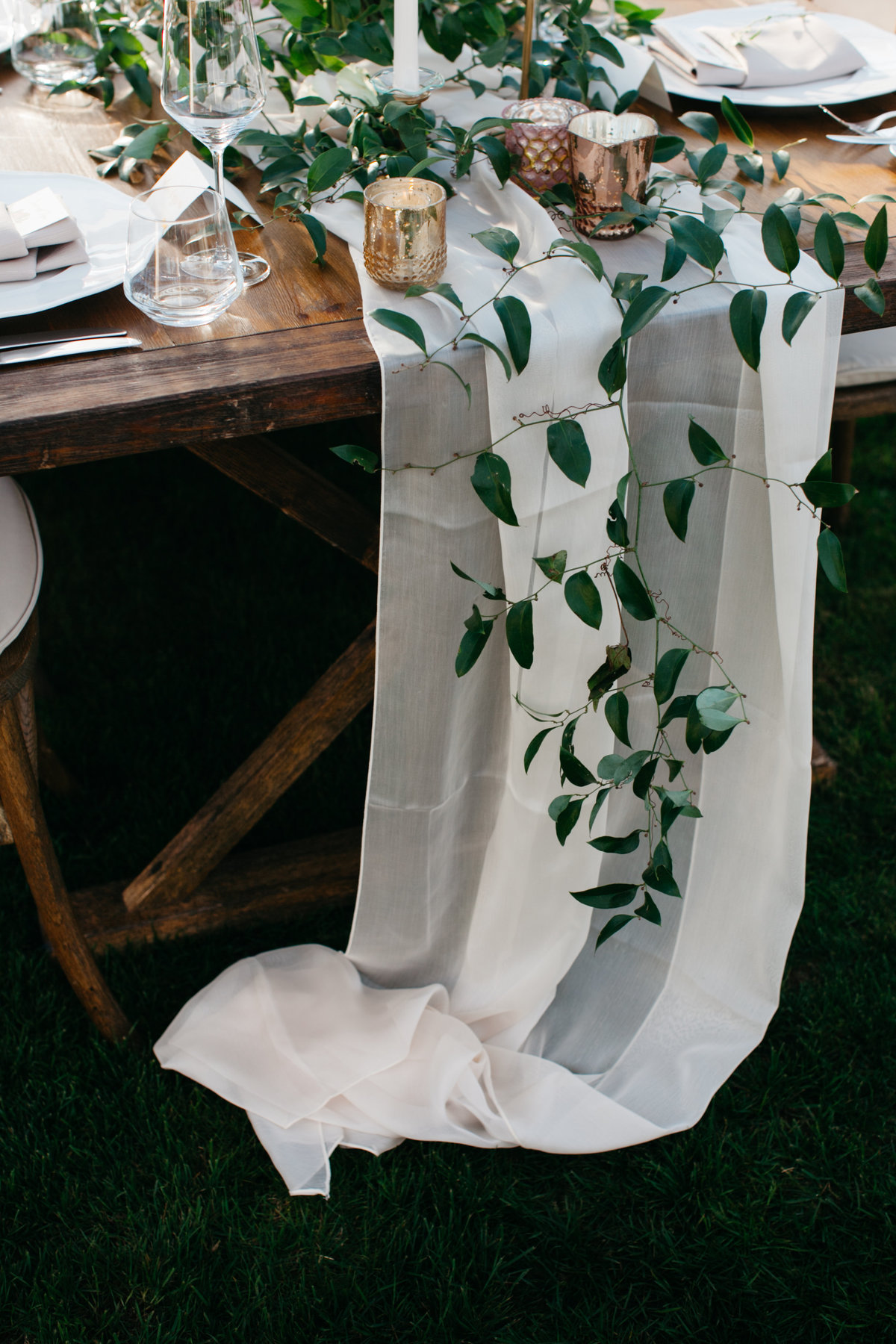 Cream sheer table runner covered in smilax vine and candles make for a truly romantic wedding.