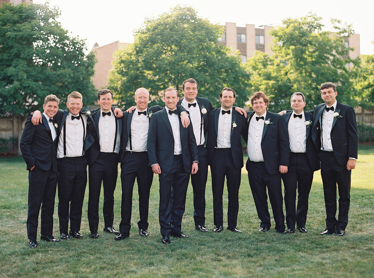 Groomsmen lined up in formal black tuxedos at Saddle Country Club.