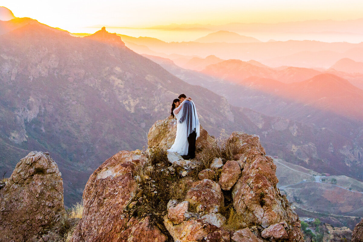 Bride and groom embrace on a mountain top