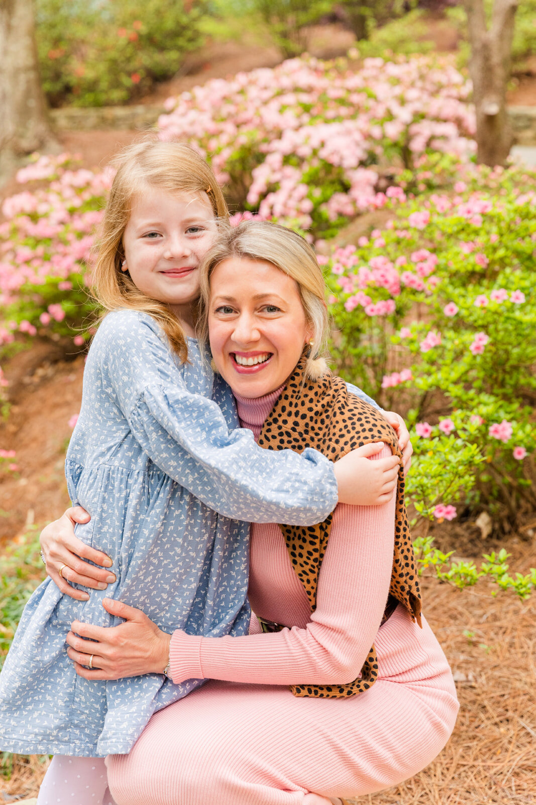 Mum in pink dress and toddler daughter in white and blue dress hugging in Ravinia Dunwoody GA