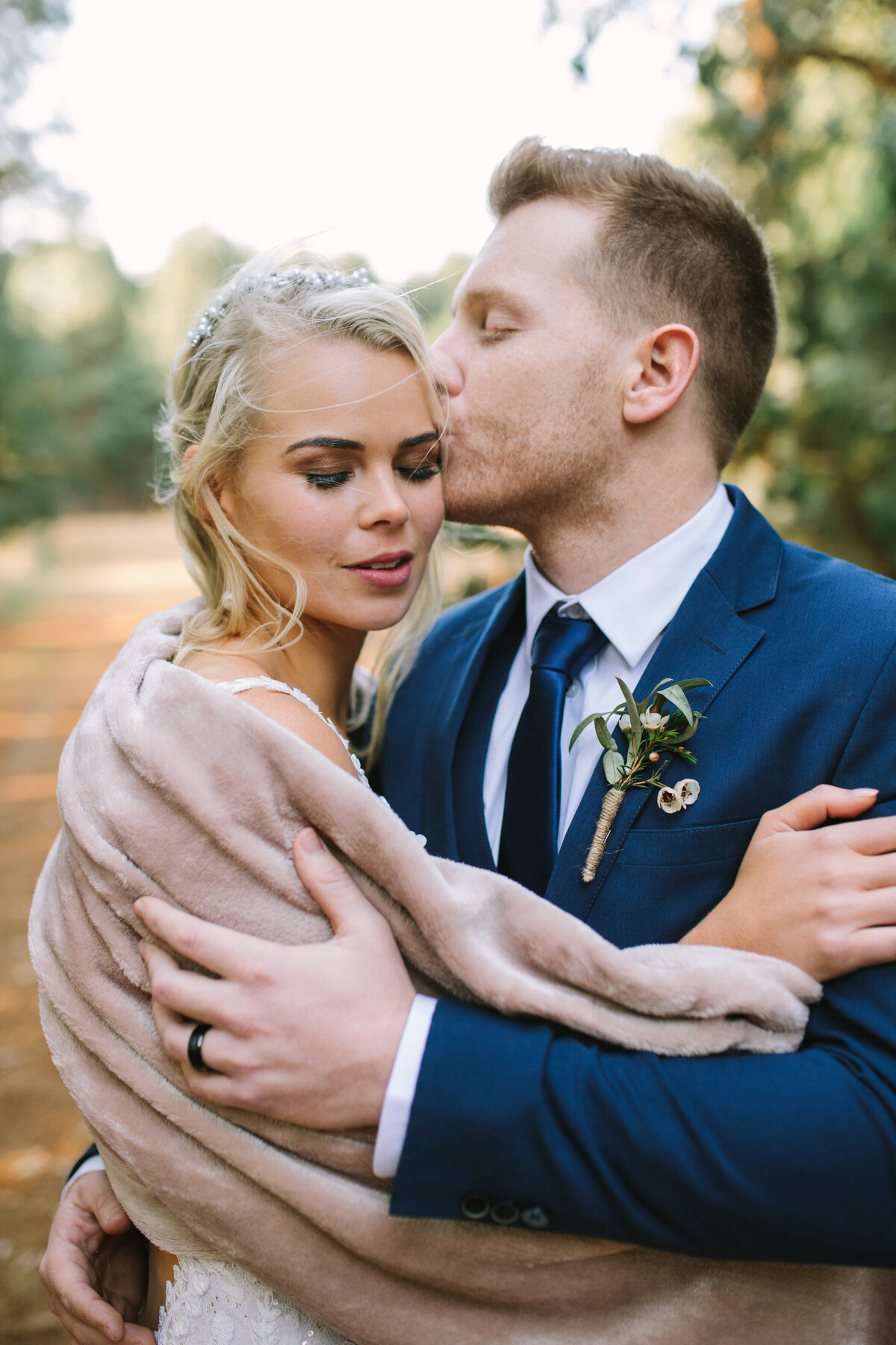 Groom gently kisses the bride on her temple. 