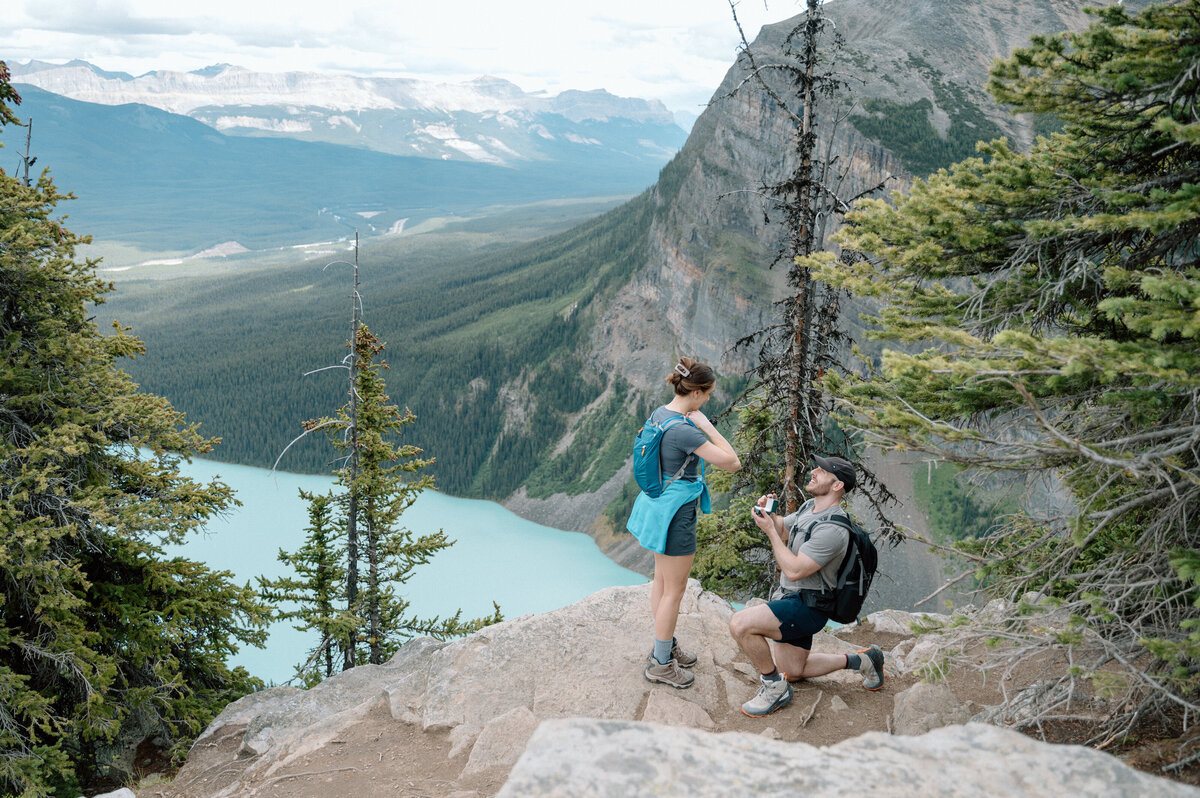 Romantic proposal on rocky overlook at lake louise, captured during a stunning proposal session during the big beehive hike.