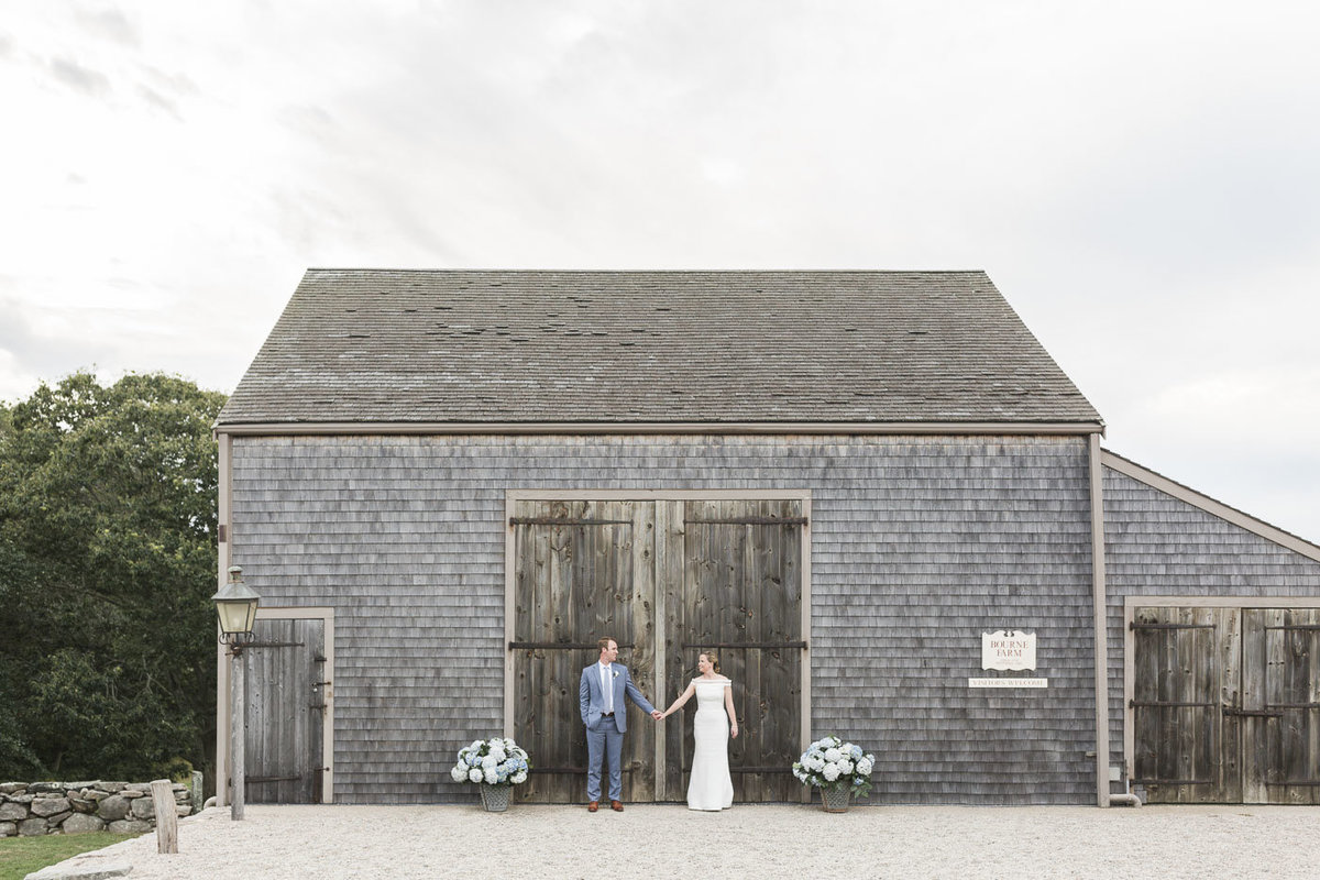 Bride and Groom standing in front of barn