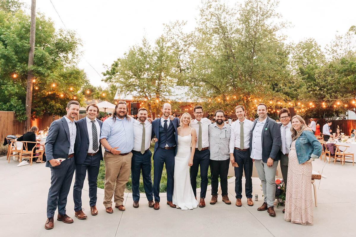 A group of people smile at the camera at a backyard wedding reception In Boise. 