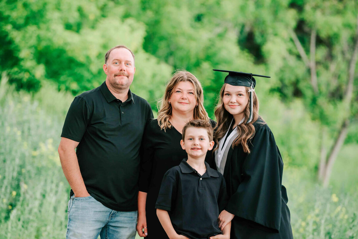 A family portrait in the trees. Graduate wearing her cap and gown. 