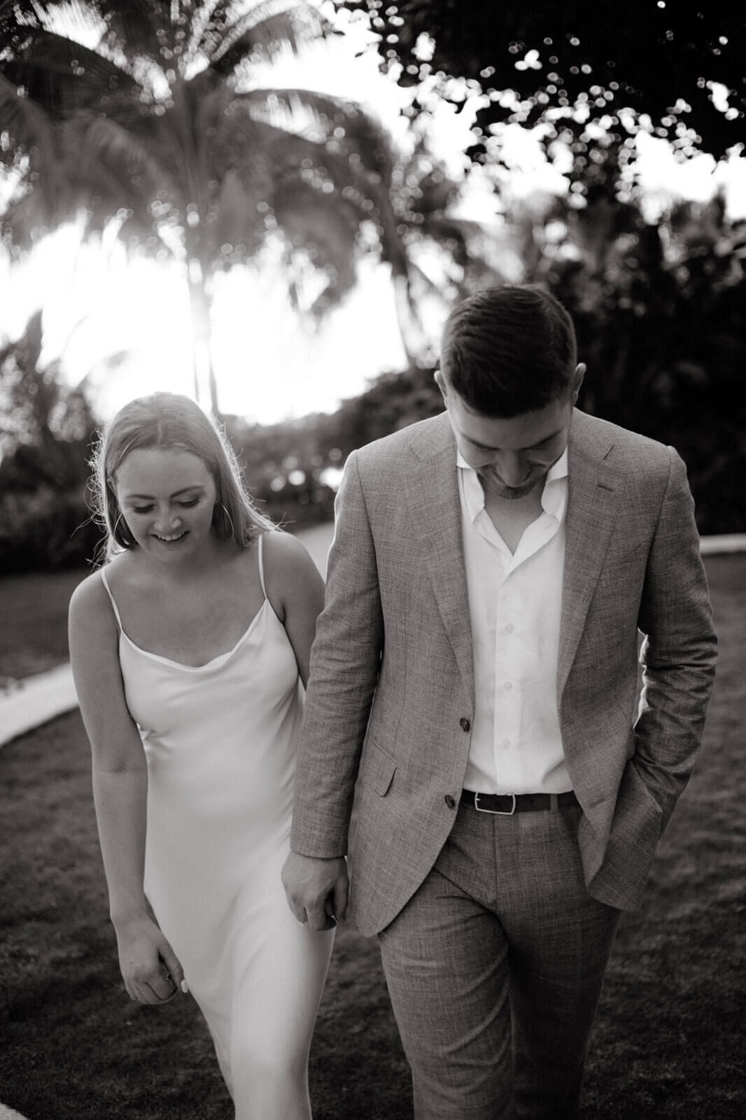 Black and white photo of the engaged couple walking in the garden of Round Hill Hotel and Villas, Jamaica.